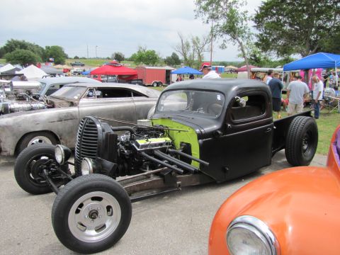 2006 BMW 5 Series - A custom hot rod pickup truck is displayed at an outdoor event with other vehicles and tents in the background.