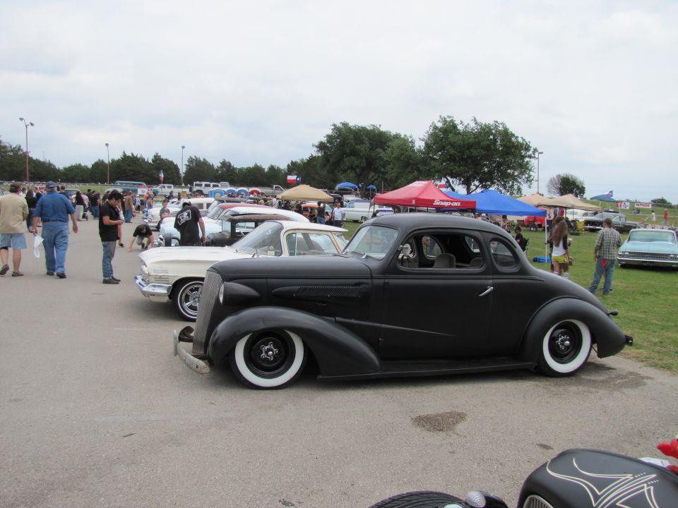 Black hot rod coupe with whitewall tires parked at an outdoor car show
