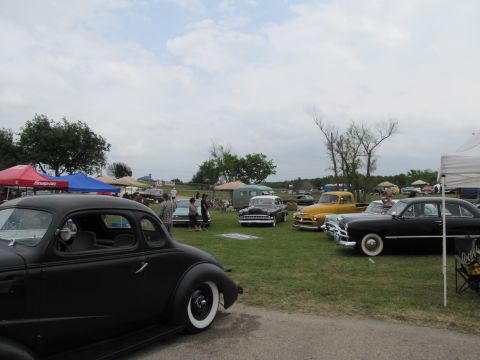 2006 BMW 5 Series - A gathering of vintage automobiles displayed outdoors, with tents and trees visible.