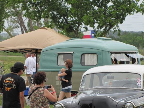 2006 BMW 5 Series - A vintage trailer and a classic car are visible at an outdoor event, with people gathered around.
