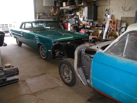 1960 Ford Ranchero - Two classic cars, a teal coupe and a blue vehicle, are undergoing repairs in a workshop setting.
