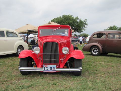 2006 BMW 5 Series - A classic red truck is the main focus, with other vintage vehicles and tents visible in a grassy outdoor setting.