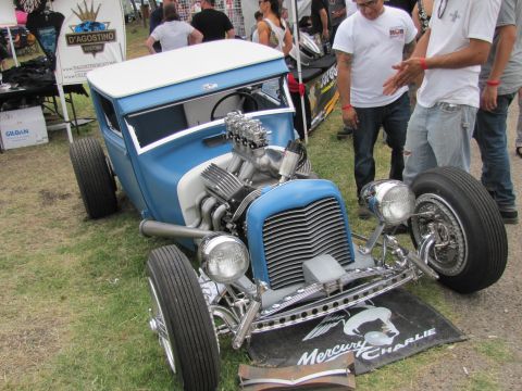 2006 BMW 5 Series - A custom blue hot rod with a prominent chrome engine and white roof is displayed at an outdoor event.