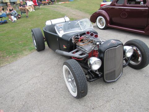 2006 BMW 5 Series - A custom hot rod with exposed engine and wide tires sits on pavement, with another classic car in the background.