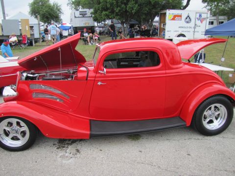 2006 BMW 5 Series - A bright red coupe hot rod is displayed with its hood and trunk open at an outdoor event.