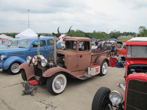 2006 BMW 5 Series - Custom hot rod pickup truck with steer horns and dual exhaust stacks at an outdoor car show.