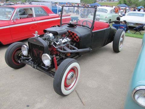 2006 BMW 5 Series - A custom hot rod with an exposed engine sits parked next to a vintage red car at an outdoor event.