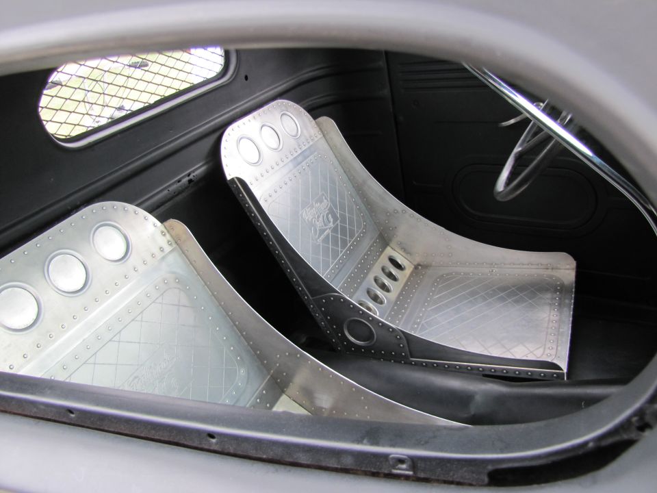Two custom aluminum racing seats with diamond plate patterns and visible rivets inside a vehicle