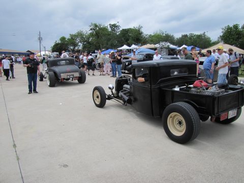 2006 BMW 5 Series - Two classic hot rod vehicles are on display at an outdoor event with spectators gathered.