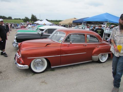2006 BMW 5 Series - A row of classic cars at an outdoor event, with a customized orange sedan in the foreground.