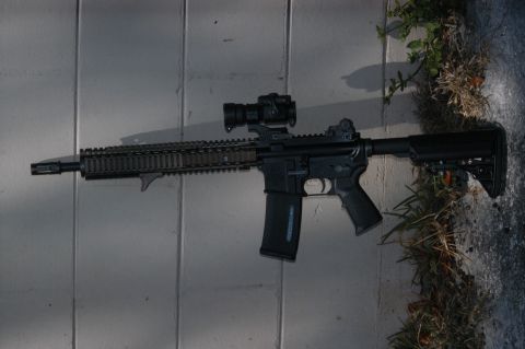 1996 Ford Bronco - An AR-15 style rifle with an optic and extended magazine rests on a textured surface.