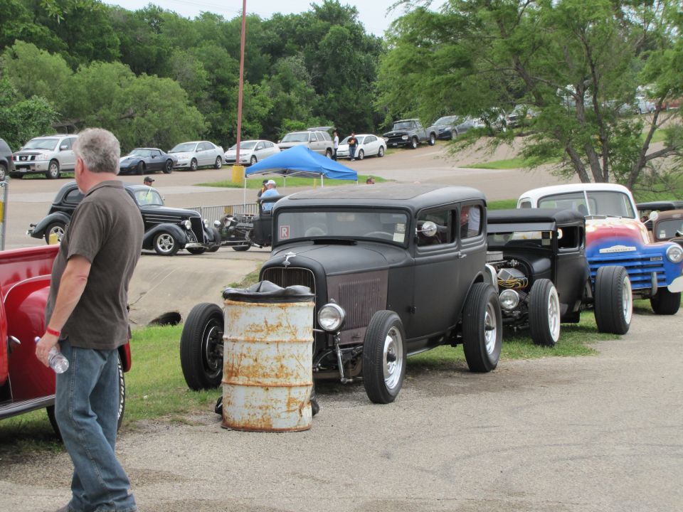 Black hot rod sedan with exposed engine and barrel in front