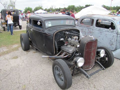 2006 BMW 5 Series - A black hot rod coupe is parked next to another car at an outdoor event.