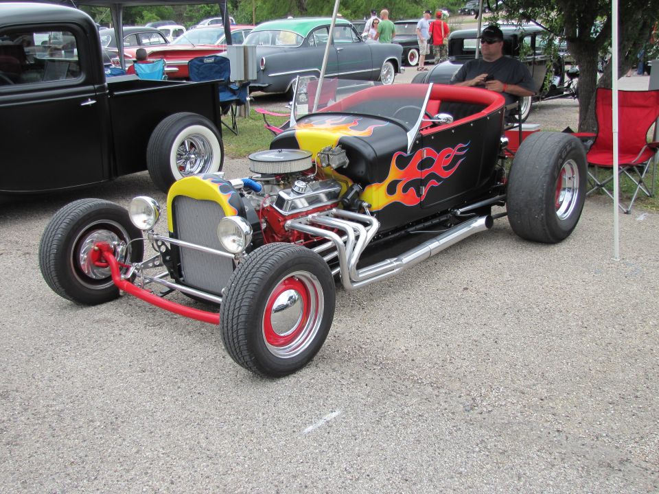 Hot rod roadster with flames painted on the side, exposed engine, and red accents