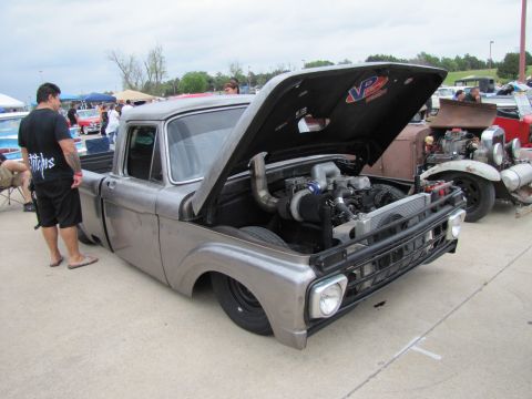 2006 BMW 5 Series - A customized pickup truck with its hood up, revealing a powerful engine, at an outdoor car show.