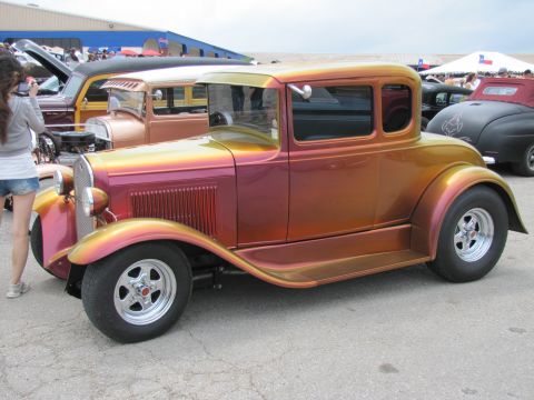 2006 BMW 5 Series - A custom hot rod coupe with an iridescent paint job is displayed at an outdoor event.