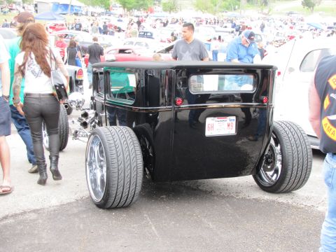 2006 BMW 5 Series - Custom hot rod with wide rear tires and chrome rims at an outdoor car show.