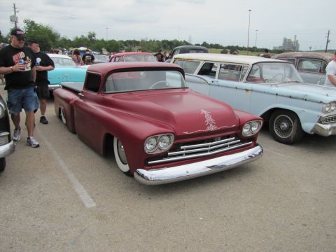 2006 BMW 5 Series - A custom red pickup truck is parked next to other vehicles at an outdoor event.
