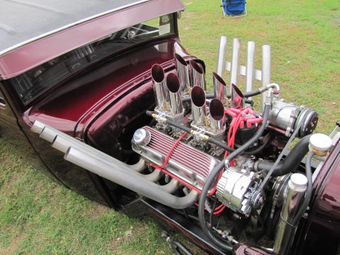 2006 BMW 5 Series - A highly customized V8 engine with exposed chrome stacks and headers sits in a dark red hot rod.