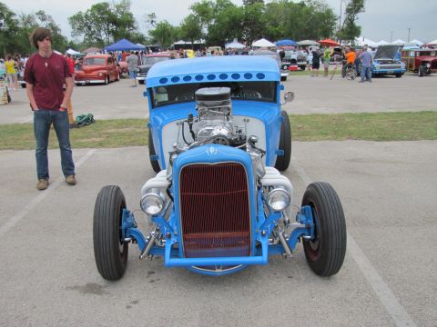2006 BMW 5 Series - A blue hot rod is displayed at an outdoor car show with other vehicles in the background.