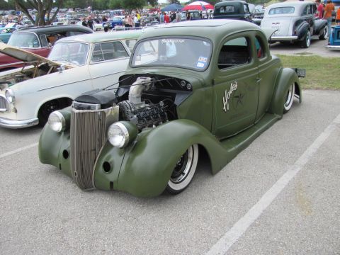2006 BMW 5 Series - A custom green hot rod coupe with an exposed engine and unique side lettering is parked at an outdoor car show.