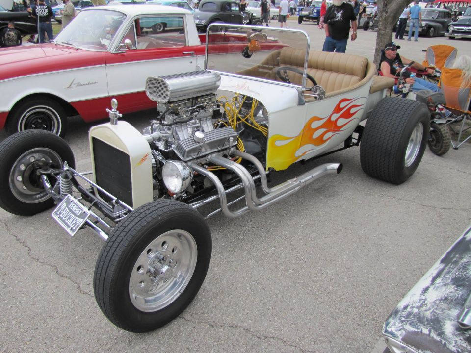 1923 Ford Model T hot rod with V8 engine and flame decals, parked next to a red and white pickup truck