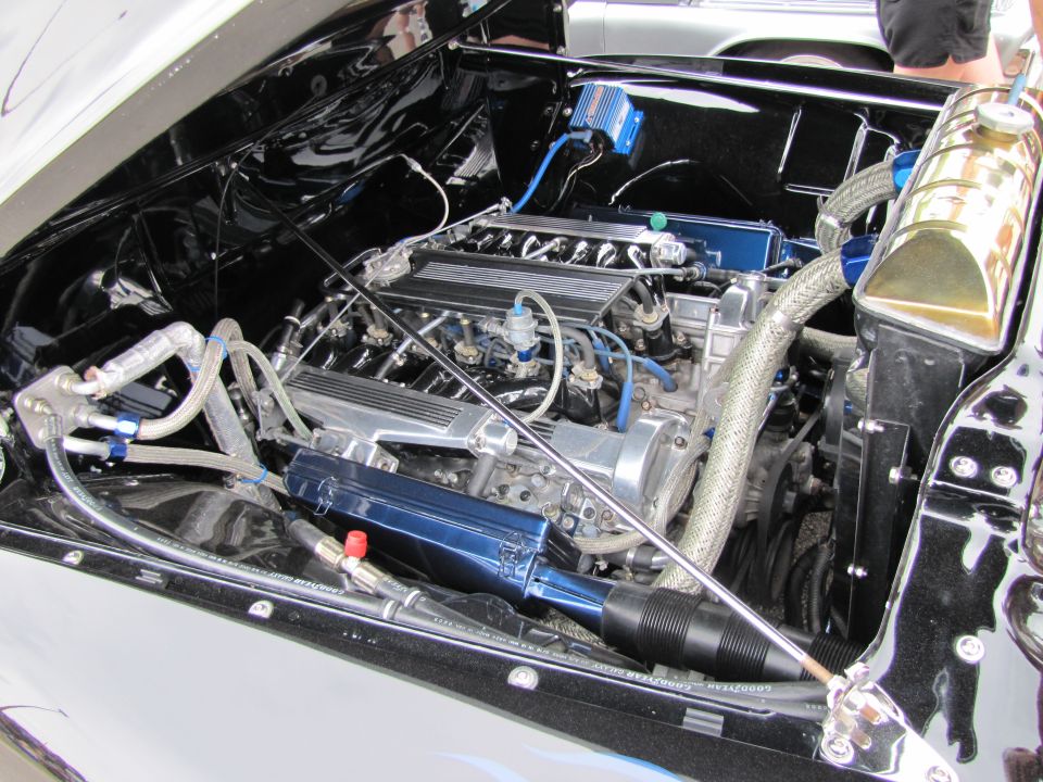 Black engine bay with a V8 engine, chrome accents, and blue components. A brass radiator tank is visible