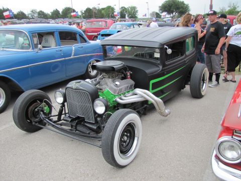 2006 BMW 5 Series - A custom hot rod with a prominent engine sits parked next to a vintage blue sedan at an outdoor event.