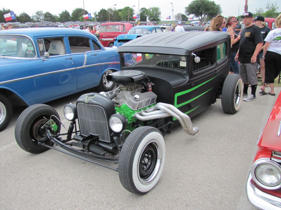 Black hot rod with green stripes and a big engine next to a blue classic car