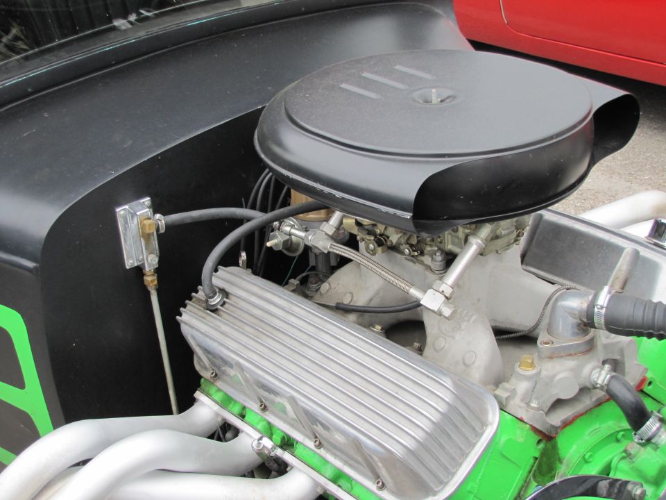 Engine with chrome valve covers, black air cleaner, and silver exhaust headers. Green painted engine block