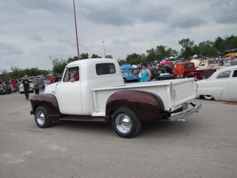 2006 BMW 5 Series - A classic two-tone pickup truck is parked at an outdoor car show with other vehicles and spectators in the background.