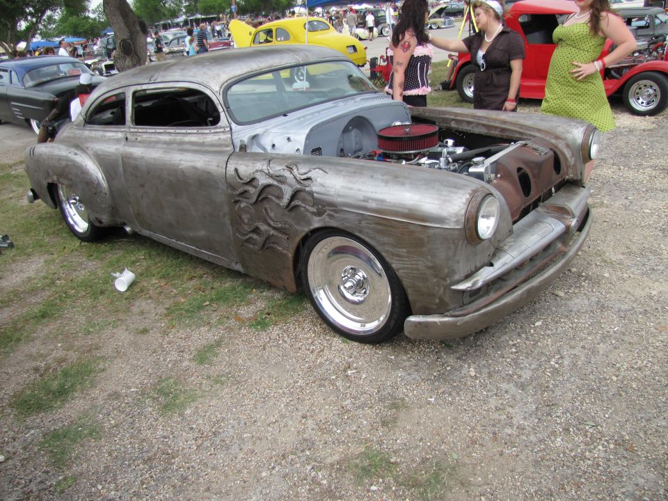 Custom hot rod with flame accents on fender, bare metal finish, chrome wheels