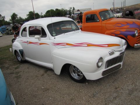2006 BMW 5 Series - A classic white hot rod with flame graphics is parked next to an orange truck with similar flame decals.