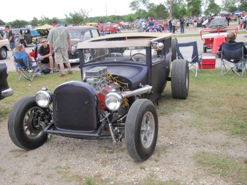 2006 BMW 5 Series - A custom hot rod with a prominent V8 engine is displayed at an outdoor car show.