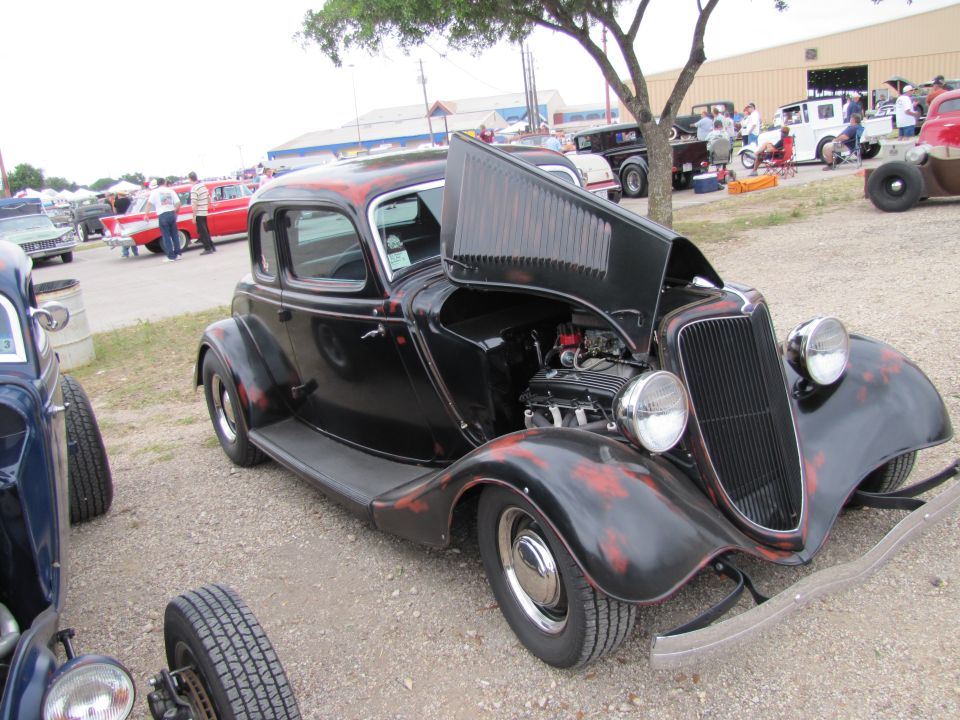 Black hot rod coupe, hood open, showing engine. Red accents on body