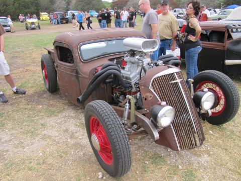 2006 BMW 5 Series - A custom-built rat rod with a powerful engine is displayed at an outdoor car show.