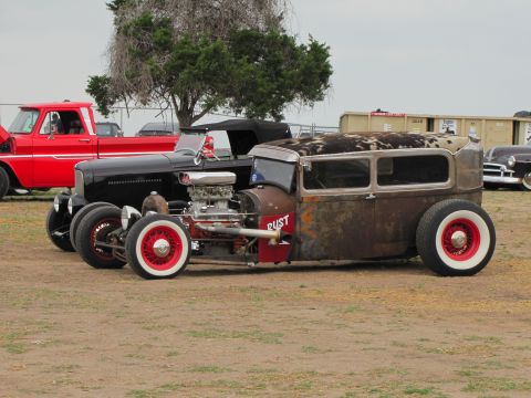 2006 BMW 5 Series - A custom rat rod with a unique cowhide roof and visible engine is parked alongside other vehicles.