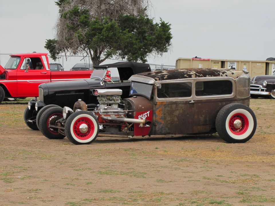 Rat rod with cowhide roof and 'RUST' painted on side, seen from the side