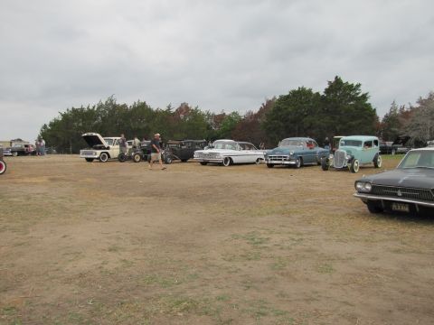 2006 BMW 5 Series - Gathering of classic automobiles at an outdoor event under a cloudy sky.