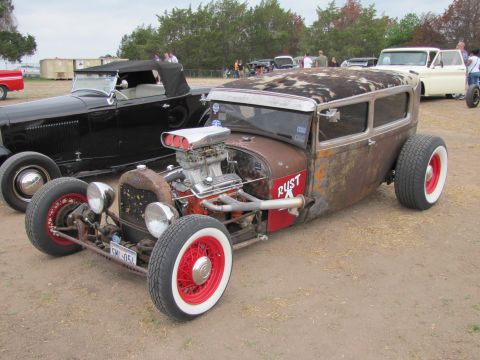 2006 BMW 5 Series - A heavily modified hot rod sedan with a prominent supercharger sits next to a black convertible at an outdoor event.