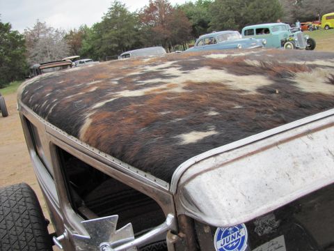 2006 BMW 5 Series - A unique hot rod with a cowhide roof is seen at an outdoor event with other vehicles in the background.