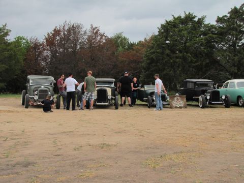 2006 BMW 5 Series - People gather around a collection of vintage hot rod cars on a cloudy day.
