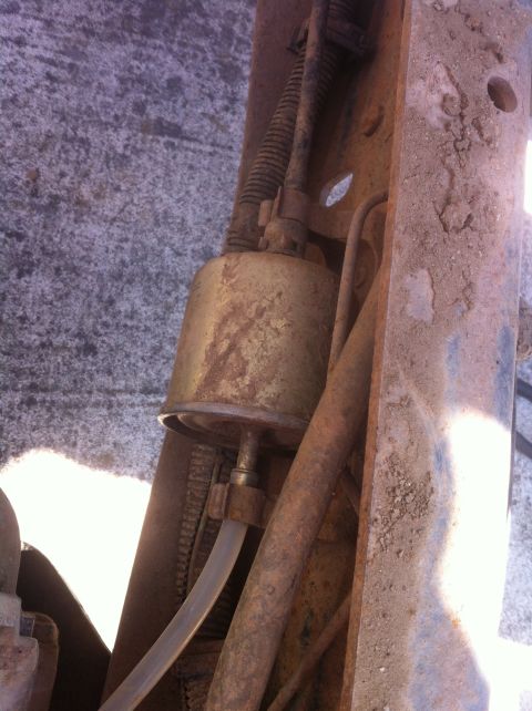 1989 Ford Bronco - Close-up of a vehicle's fuel filter and associated plumbing, showing signs of rust and wear.