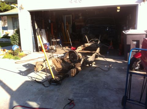 1989 Ford Bronco - Vehicle chassis and drivetrain disassembled in a garage, possibly for a tub swap project.