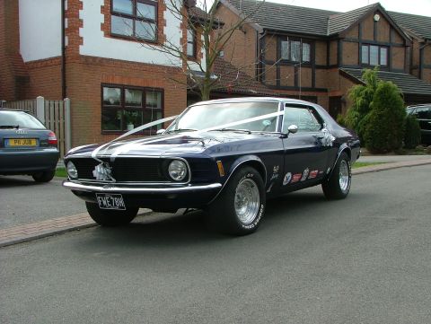 1970 Ford Mustang - Dark blue 1970 Ford Mustang with white wedding ribbons and racing decals on the fender.