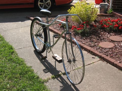 1994 Ford Bronco - A cruiser bicycle sits on a sidewalk next to a flower bed and a parked car.