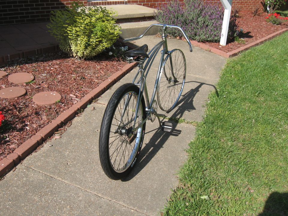 Chrome cruiser bicycle with wide handlebars and black seat parked on a sidewalk