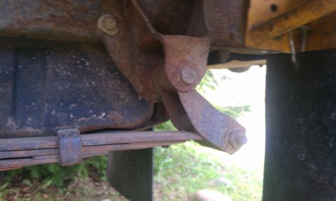 1978 Ford Bronco - Underside view of a rusty leaf spring and suspension bracket.