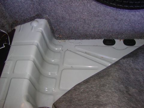 1991 Ford LTD Crown Victoria - Close-up of the trunk's metal floor, showing its ribbed structure and some carpeted areas.
