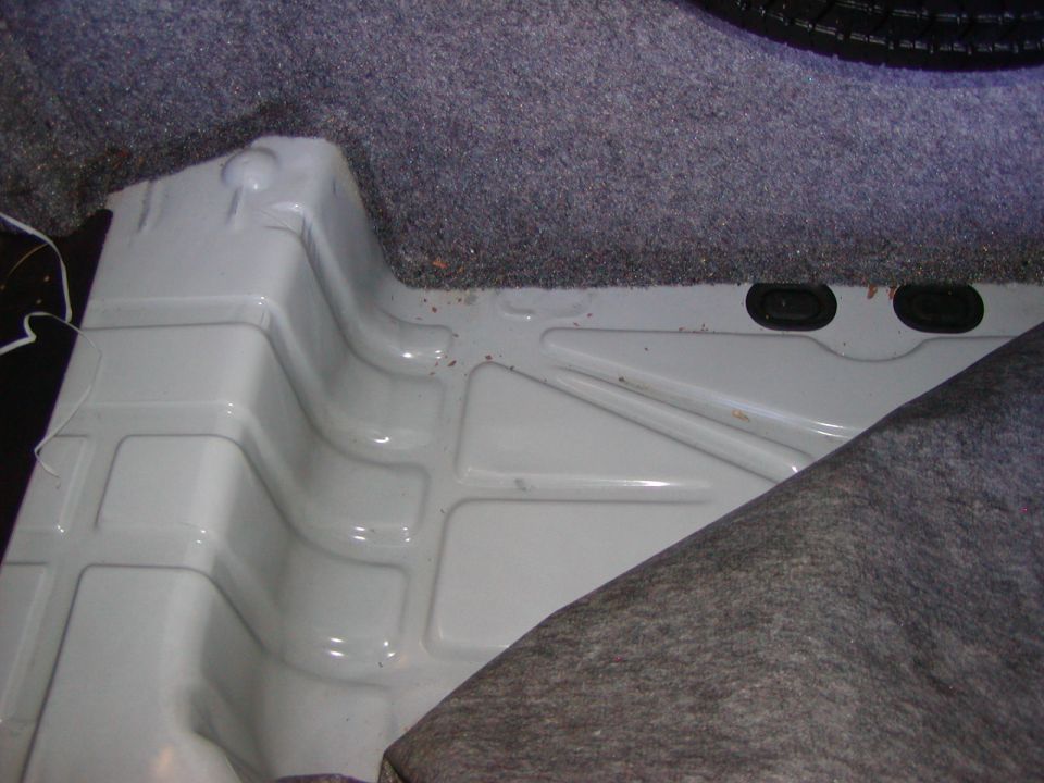 Car's trunk floor with white painted metal and gray carpet lining